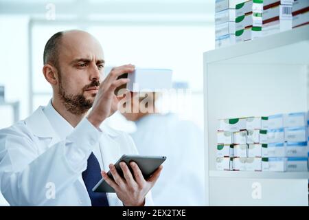 pharmacist is reading the information on the screen of his digital tablet. Stock Photo