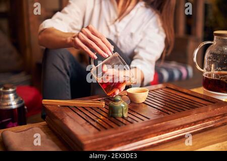 Female hands pouring tea into small ceramic cup Stock Photo