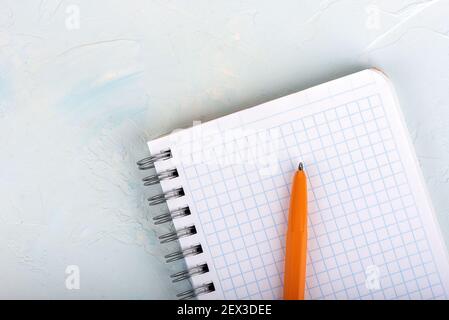 Orange ballpoint pen on a blank sheet of notepad. Top view. Copy space. Stock Photo