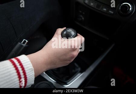 Hand holding the transmission gear shift stick of a car. View from inside the car. Stock Photo