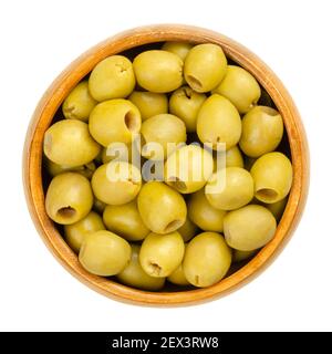 Pickled and pitted small green table olives in a wooden bowl. Green fruits of Olea europaea, unripe picked, cured and fermented before preservation. Stock Photo