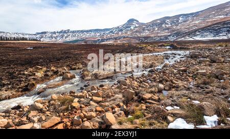 Mountains winter snow water run off into river stones high route pass contrasting scenic panoramic landscape. Stock Photo
