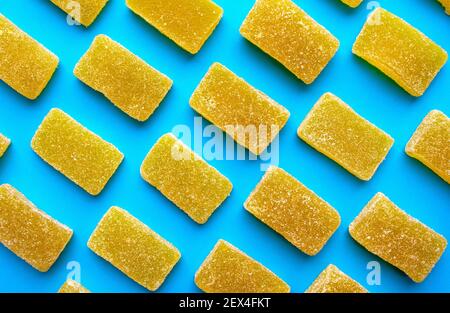 Yellow jelly candies pattern on a blue background. Yellow rectangular shaped marmalade on colorful pattern. Top view Stock Photo
