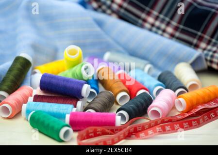 Set of colorful sewing threads, close-up. Fabric for sewing in the background. Stock Photo