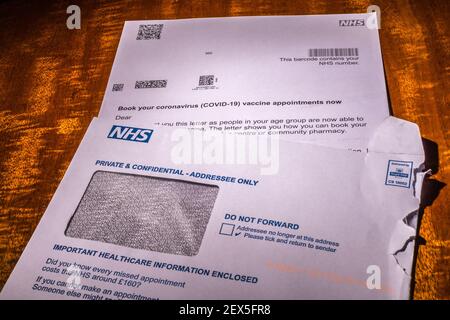 NHS invitation letter to book a coronavirus vaccination for a person over 60 years old with guidance leaflet. Retouched to remove personal information. Stock Photo