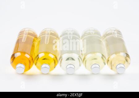 Collection lying transparent bottles with different pale colors liquid, cosmetic product, perfume or drink and silver cap on white background, top and Stock Photo