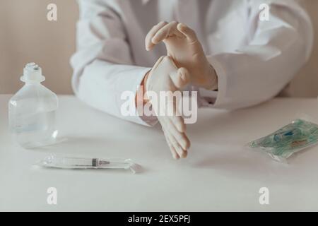 Medicine doctor putting on protective gloves before examination on a white table. syringe Stock Photo
