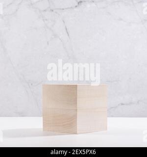 Wood cube podium with sunlight and shadow for presentation and product display on white wood table and marble wall, square. Stock Photo