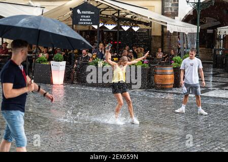 Prague / Czech Republic - 08 01 2020: Happy adult woman splashing in the rain puddles Stock Photo