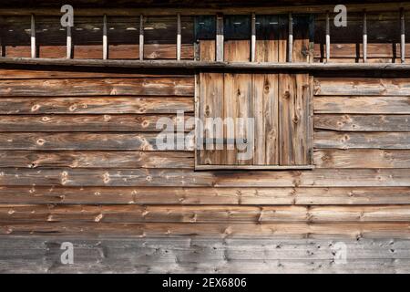 Exterior wall of a rustic hut with closed window shutter and ladder Stock Photo