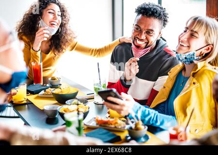 Friends having fun drinking at cocktail bar - Multiracial people talking together at restaurant reopening - New normal life style concept Stock Photo