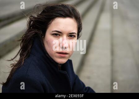 Outdoors portrait of a 28 year old white woman with brown hair sitting on a long staircase in the city Stock Photo