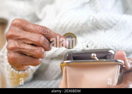 Close up of elderly women hand saving coins in a wallet  Stock Photo