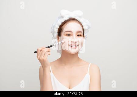 Skin care. Female applying black purifying mud mask, cosmetic healing clay to half face, using brush. Beauty and wellness. Spa and acne treatment. Stock Photo