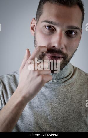Portrait of a young man scratching his beard with a finger while he is thinking about something Stock Photo