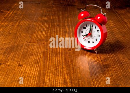 Old fashioned red alarm clock on the old wooden table background Stock Photo