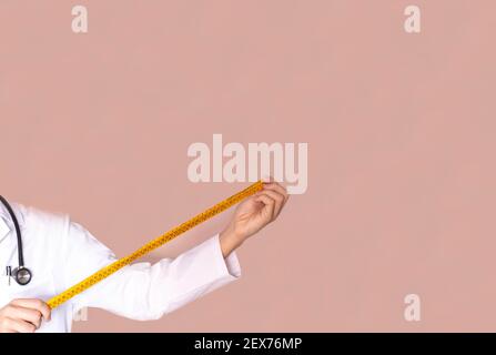 selective focus of an endocrine doctor and nutritionist holding a measuring tape to check the weight and measurement of his patients health concept Stock Photo