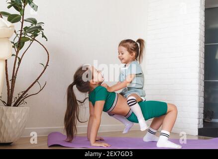 two little girls in sportswear sitting at fitness studio, children
