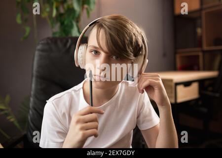 Little boy wearing headphones during online education course, lesson, view of screen. Using headphones. Easy, comfortable usage concept, education, online, childhood, modern technologies for remotion. Stock Photo