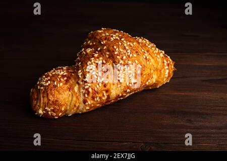 Croissant with sesame seeds isolated on a wooden background. Stock Photo