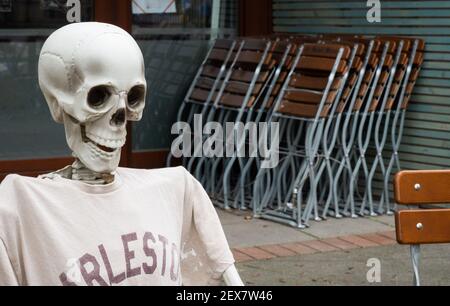 04 March 2021, Lower Saxony, Hanover: A skeleton sits outside a restaurant closed due to the Corona pandemic in Südstadt. The lockdown in Germany is extended until March 28. Photo: Julian Stratenschulte/dpa Stock Photo