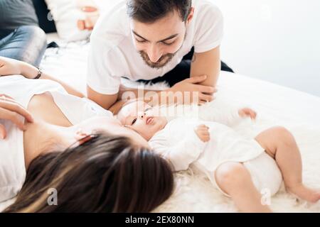 Stock photo of happy parents lying in bed with their adorable young baby. Stock Photo