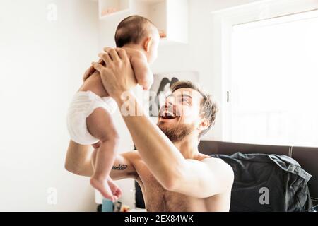 Stock photo of happy father sharing cute moment with his newborn baby in the bedroom. Stock Photo
