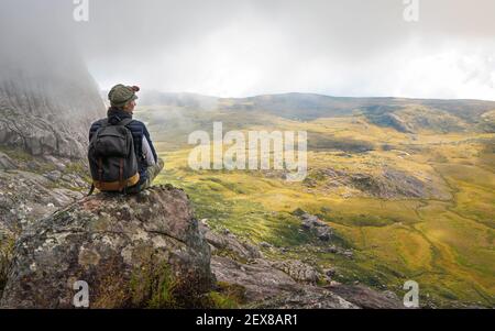 Young woman in sports clothing sitting on rocks enjoying the scenery of Andringitra national park, large stones massif background, during hike to pic Stock Photo