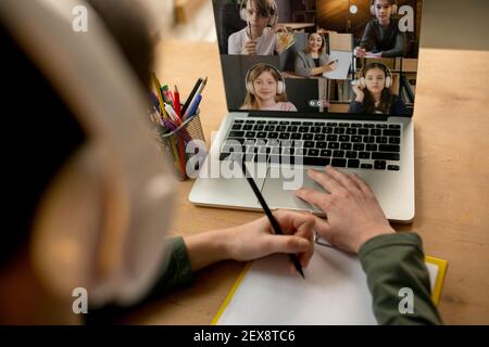 Little boy studying by group video call, use video conference with teacher, listening to online course. Using stationery, notebook. Easy, comfortable usage concept, education, online, childhood. Stock Photo