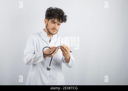 Young thoughtful doctor looking at his stethoscope Stock Photo