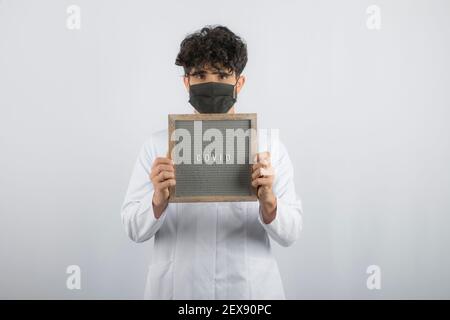 Curly haired young doctor holding board with both hands Stock Photo