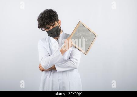 Curly haired young doctor holding board and looking at camera Stock Photo
