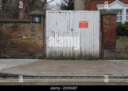 Painted White Wooden Gate, with No Parking Sign and Brick Wall Background Stock Photo