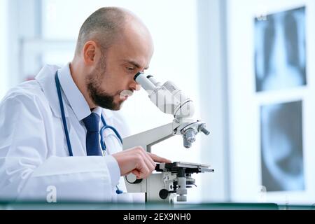 doctor looking through a microscope in the lab. Stock Photo