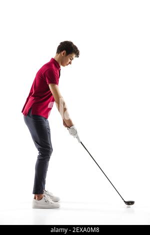Objective. Golf player in a red shirt isolated on white studio background with copyspace. Professional player practicing with emotions and facial expression. Sport, motion, action concept. Stock Photo