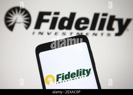 In this photo illustration a Fidelity Investments logo is seen on a smartphone and a pc screen. Stock Photo