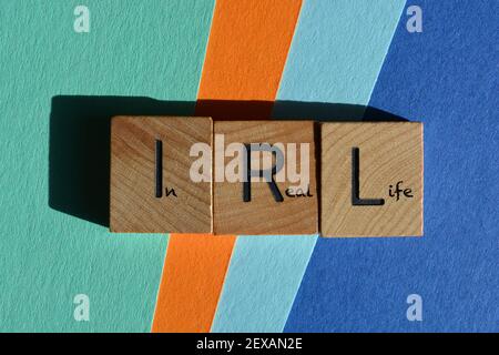 IRL, In Real Life, acronym and words in wooden alphabet letters isolated on colourful background Stock Photo