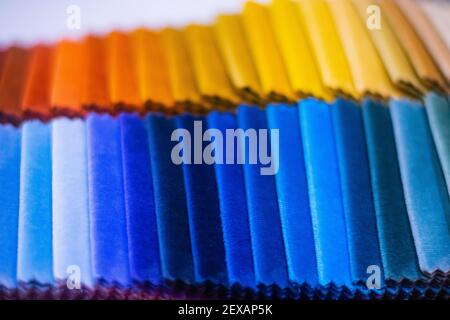 Closeup with shallow depth of field on colorful velour fabric samples in two lines divided to warm colors and cold colors, luxury furniture fabric sam Stock Photo
