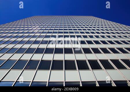 Low angle view on skyscraper facade with geometric symmetrical pattern lines against deep blue cloudless sky Stock Photo