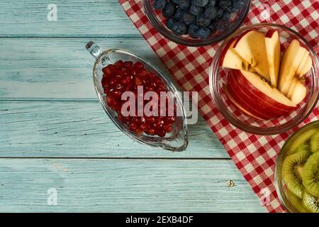 Three cups of blueberry, apple and kiwi on the blue wooden background. Stock Photo