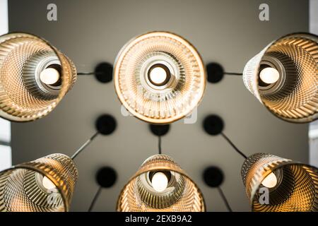 Looking up to ceiling at cool hanging symmetrical lights turned on and glowing with glass lamp shades in modern new building Stock Photo
