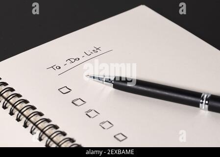 high angle view of handwritten to do list on spiral notepad on dark desk background Stock Photo
