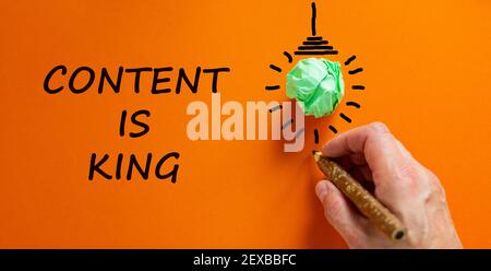 Content is king symbol. Businessman writing words 'Content is king', isolated on beautiful orange background. Light bulb icon. Business and content is Stock Photo