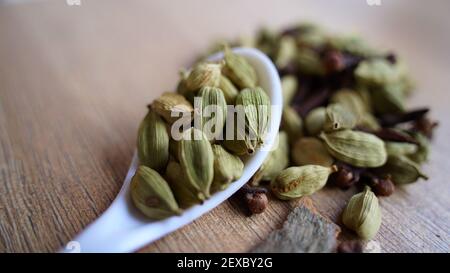 Green cardamom pods on rustic wooden background. Indian spices macro view. elaichi (Elettaria cardamomum) Stock Photo