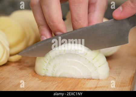 Closeup of man hands cutting an onion. Ingredient preparation concept. Stock Photo