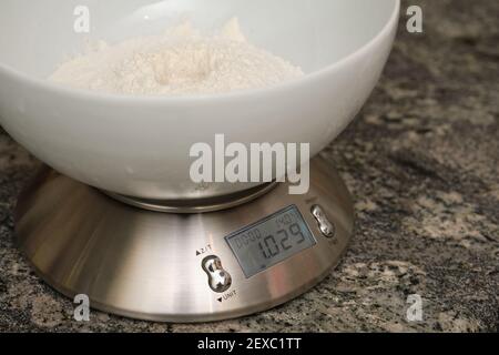 Weighing flour for baking on a digital scale. Preparing bread at home. Stock Photo