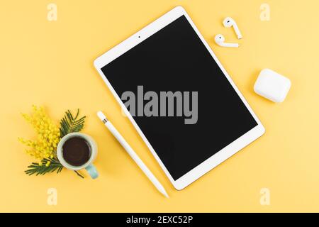 Tablet with headphones and pencil on yellow background. Top view. Copy space. Stock Photo