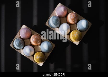 High angle of colorful Easter eggs in egg carton on black background Stock Photo