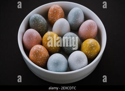 Overhead view of colorful Easter eggs in bowl on black background Stock Photo