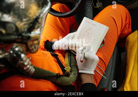 Man dressed as an astronaut draws a rocket on the notebook Stock Photo